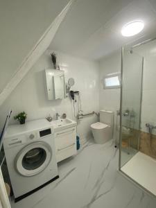 a white bathroom with a washing machine and a shower at Villa Luiza in Şura Mare
