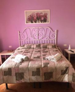um quarto roxo com uma cama com toalhas em B&B da Cinzia em Pontecagnano