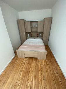 Bett in einem kleinen Zimmer mit Holzböden in der Unterkunft Maison des Vignes in Tabanac