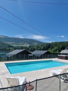 a swimming pool with two white chairs next to it at Chalet bord de lac avec piscine 2A in Laffrey