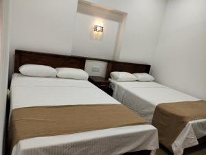 2 camas en una habitación con paredes blancas en Jacks Lounge and Hotel, en Kandy