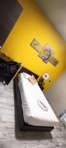 ein Schlafzimmer mit einem weißen Bett und einer gelben Wand in der Unterkunft Millaenya Inn in Entratico