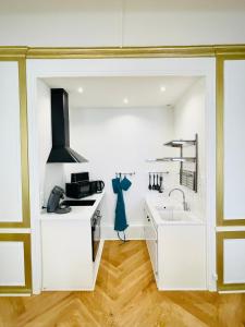 - une cuisine blanche avec évier et cuisinière dans l'établissement Charmant appartement haut de gamme, à Salins-les-Bains