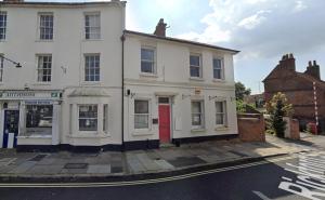 a white building with a red door on a street at Aylesbury Studio Apartment 6 with parking in Buckinghamshire