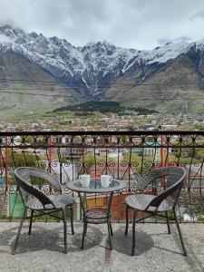 a table and chairs on a balcony with mountains at Belas guesthouse in Stepantsminda