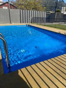 a swimming pool with blue water in a yard at Departamento con estacionamiento in Concepción