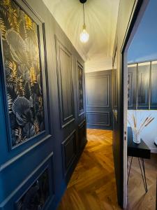 un couloir orné d'un mur bleu et d'un tableau. dans l'établissement Charmant appartement haut de gamme, à Salins-les-Bains