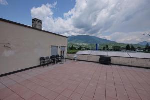 eine Terrasse mit Stühlen und ein Gebäude mit Bergen im Hintergrund in der Unterkunft B&B DIVINO in Calceranica al Lago