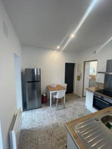 a kitchen with a table and a stainless steel refrigerator at Séjourner chez Mina in Lille