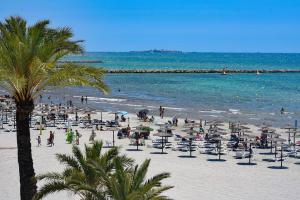 un gruppo di persone su una spiaggia con sedie e ombrelloni di Sunny Home Gran Alacant a Gran Alacant
