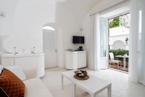 Sala de estar blanca con sofá y mesa en Villa Mariuccia Capri en Capri