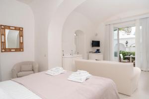 a white room with a bed and a chair at Villa Mariuccia Capri in Capri