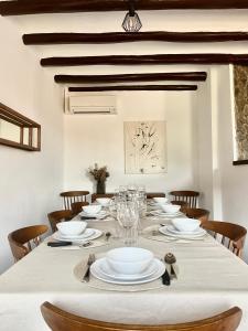 einen langen Tisch mit weißen Tellern und Weingläsern in der Unterkunft Casa Rural Cal Vellet del Priorat in La Vilella Baixa