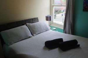 ein Bett mit zwei schwarzen Kissen und einem Fenster in der Unterkunft City Heights inquire for FREE Parking in Kent