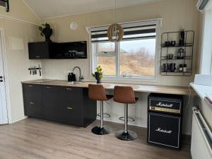 a kitchen with a counter and two stools in it at Veigakot in Akureyri