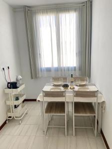 Una mesa blanca con sillas y una ventana en una habitación. en Casa Seagull, en Playa Blanca