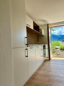 eine Küche mit weißen Geräten und einem großen Fenster in der Unterkunft Ferienwohnung Haslach in Wertach