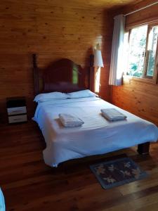 Un dormitorio con una cama grande en una cabaña. en Pousada Cajuvá, en Urubici