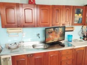 eine Küche mit Holzschränken und einem TV auf der Theke in der Unterkunft CASA 2024 - São João Campina Grande/PB in Campina Grande + 6 Fotos