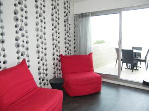 a red couch and a chair in a living room at Hôtel Le Nautic in Arcachon