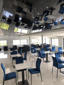 een cafetaria met tafels en blauwe stoelen en ramen bij Guest House MK Star in Belgrado