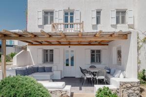 een patio met een wit huis met een houten pergola bij Healthy House Mykonos in Ornos