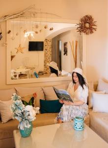 a woman standing in a living room holding a book at Summer House Collection - A Secluded Getaway in Perissa