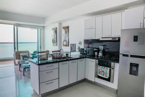 een grote keuken met witte kasten en apparaten bij Playa Cartagena Apartments in Cartagena