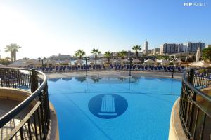 a large blue pool with chairs and umbrellas at Corinthia St George's Bay in St. Julianʼs