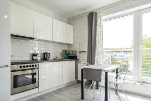 a kitchen with white cabinets and a table and a window at Pomorskie Apartamenty Bernadowska B&W in Gdynia