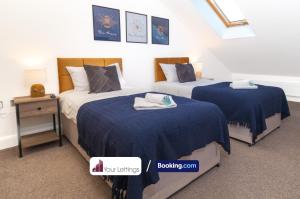 1 dormitorio con 2 camas y edredones azules en Stylish 2 Bedroom Apartment By Your Lettings Short Lets & Serviced Accommodation Peterborough With Free WiFi,Parking And More en Huntingdon