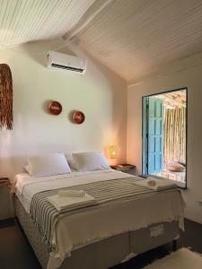 Un dormitorio con una cama grande y una ventana en Pousada Quintal Caraíva en Caraíva