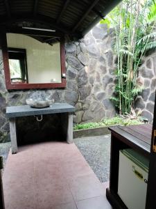a stone bathroom with a mirror on a stone wall at BINTANG MUNDUK in Munduk