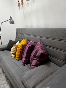um sofá cinzento com quatro almofadas coloridas em Penthouse, 3Bed in Heart of Malasana em Madri