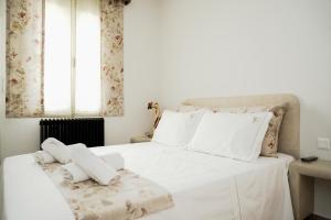 un letto bianco con lenzuola e cuscini bianchi di Filokalia 4 Veins - Vacation House with Sea View a Karistos