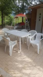 a white picnic table and four white chairs at Paisible Chalet 5 personnes maxi en option 8 pers SPA in Largentière +4 photos