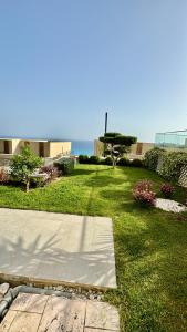 a yard with grass and a sidewalk and the ocean at Green Coast, Palase 148 in Palasë +5 photos