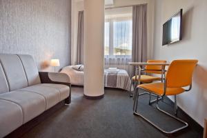 una camera d'albergo con divano, tavolo e sedie di Urocza Art Pensjonat a Krynica-Zdrój