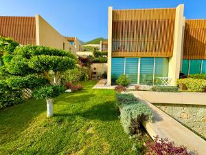 a garden in front of a building with a tree at Green Coast, Palase 148 in Palasë