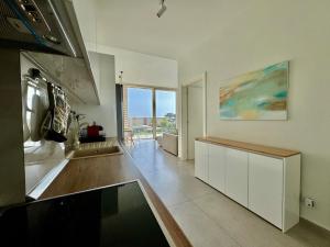 a kitchen with white cabinets and a large window at Green Coast, Palase 148 in Palasë