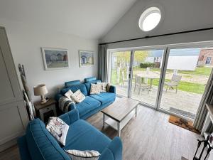 a living room with a blue couch and a table at Azure Beach House - Part of the The Bay Filey Holiday Village with pool, gym and direct beach access, pub, restaurant, tennis and meadows walks in Filey