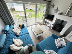 a living room with a blue couch and a table at Azure Beach House - Part of the The Bay Filey Holiday Village with pool, gym and direct beach access, pub, restaurant, tennis and meadows walks in Filey