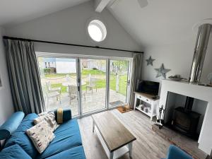 a living room with a blue couch and a sliding glass door at Azure Beach House - Part of the The Bay Filey Holiday Village with pool, gym and direct beach access, pub, restaurant, tennis and meadows walks in Filey