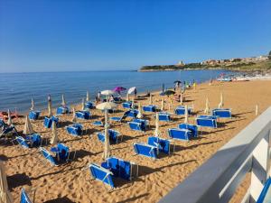 a group of blue chairs and umbrellas on a beach at Villa Ida in Capo Rizzuto