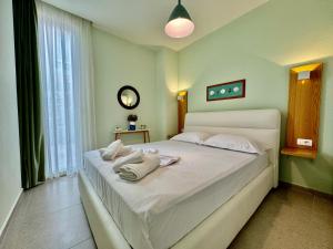 a bedroom with a white bed with towels on it at Green Coast, Palase 148 in Palasë