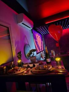 a table with two plates of food and a heart balloon at Logement Romantique Jacuzzi spa in Vieille-Toulouse