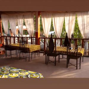 Kiriboungni chez sylfatou في Tahire: غرفة طعام مع طاولتين وكراسي وستائر
