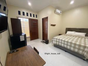 1 dormitorio con cama, mesa y TV en Light House Residence Denpasar Bali, en Denpasar