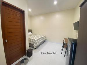 Habitación con puerta, cama y TV en Light House Residence Denpasar Bali, en Denpasar