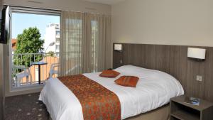 a bedroom with a bed and a large window at Hôtel Le Nautic in Arcachon